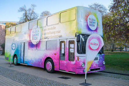 Bild vom Bus von Glück sucht dich, mit dem Logo bunte Farbe um einen weißen Kreis mit der Innenschrift Glück sucht dich vor dem Carlowitz Congresscenter