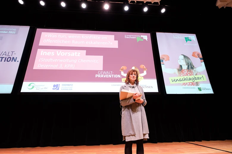Eine Frau auf der Bühne vor der Bildschirmpräsentation.