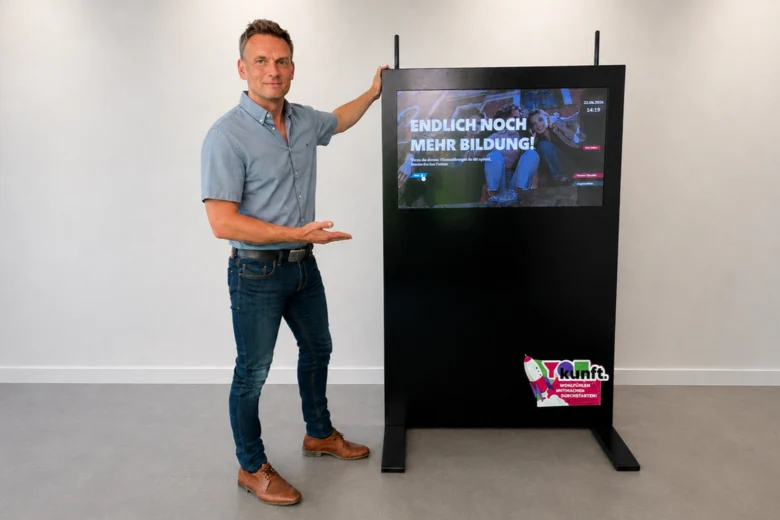 Ronny Türk stehend neben einem Rollup, auf dem Inhalte der Themenausstellung vermerkt sind